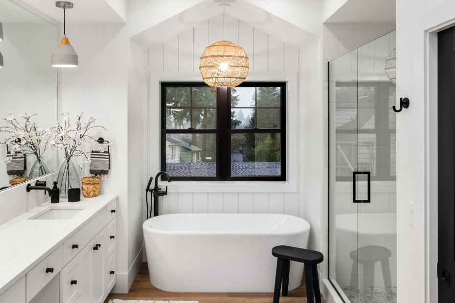 white bathroom with black fixtures featured and a standing tub in a small space