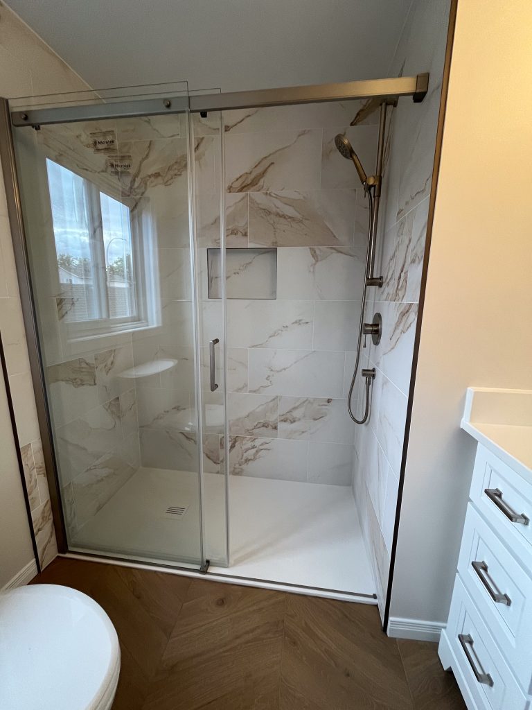 a glass shower with a marble tile floor