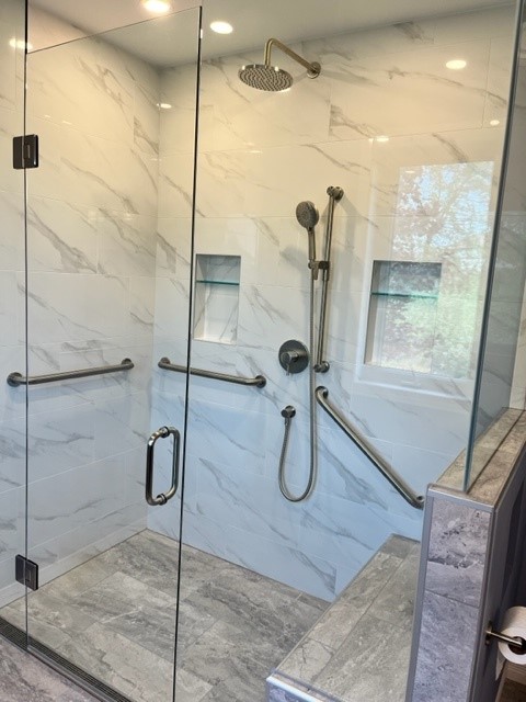 a shower with a glass door and grab bars